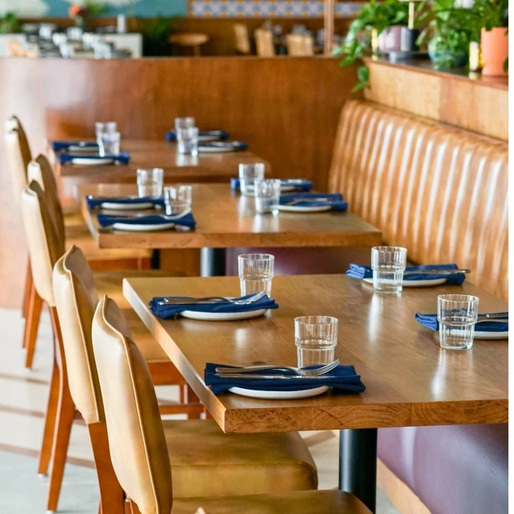 Salle de restaurant avec banquette en cuir, chaises et tables dressées