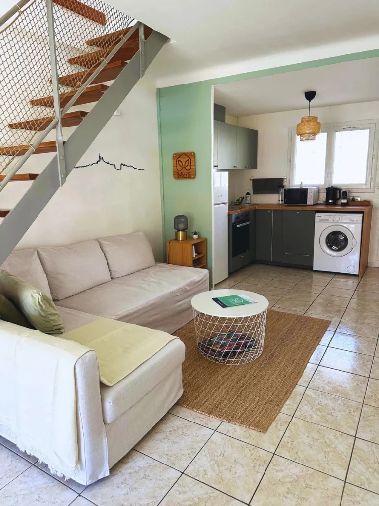 Canapé beige et table basse face à la cuisine vert sauge, projet Gouffé par Maison Solthée, architecte d'intérieur à Marseille