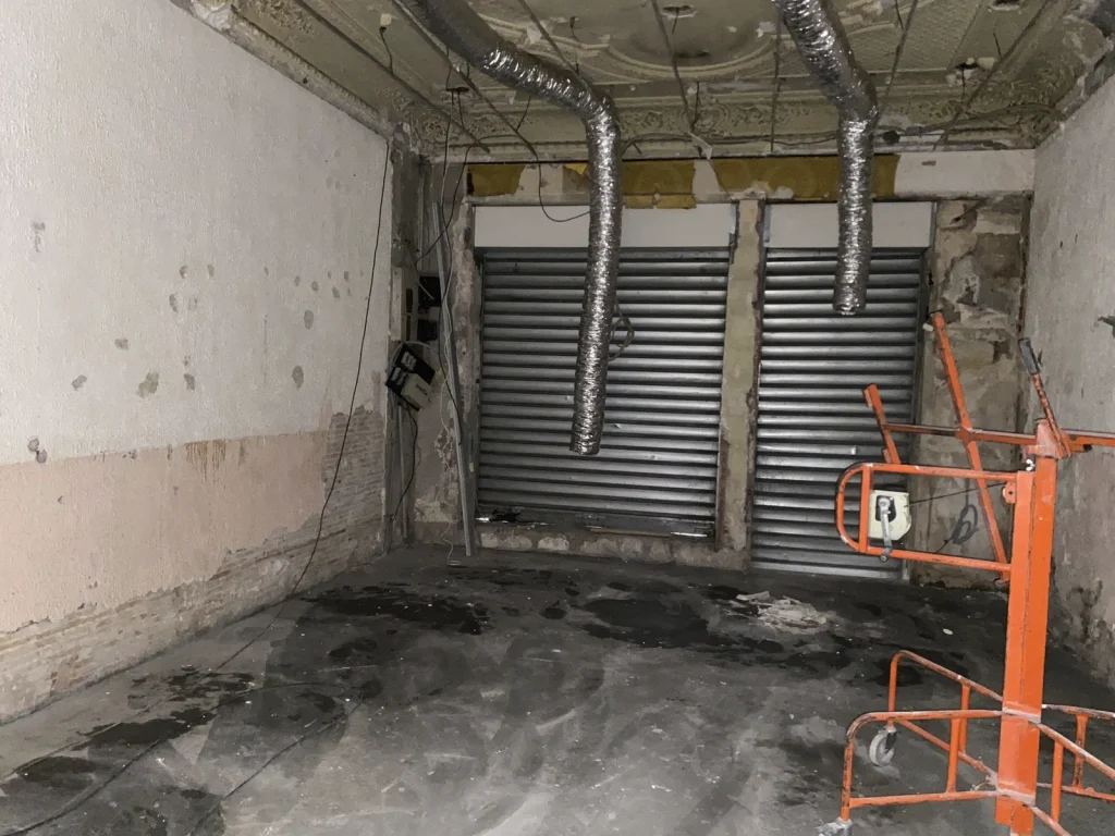 Local avant travaux, rideaux métalliques, gaines apparentes et plafond brut, projet Meinado par Maison Solthée, architecte d'intérieur à Marseille