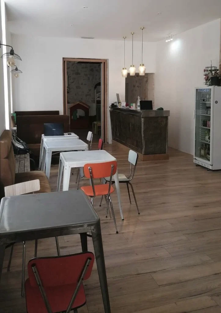 Salle du café associatif avec tables, chaises colorées et comptoir, projet Meinado par Maison Solthée, architecte d'intérieur à Marseille