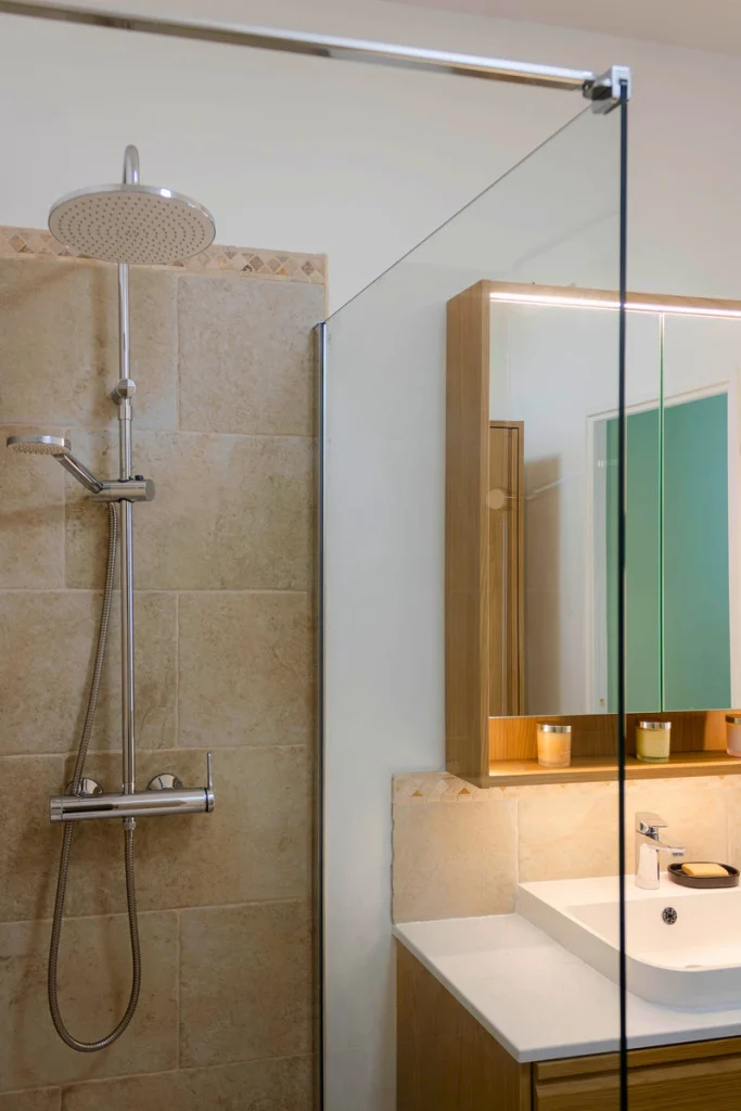 Douche avec faïence beige effet pierre et niche en chêne, projet Parengon par Maison Solthée, architecte d'intérieur à Marseille