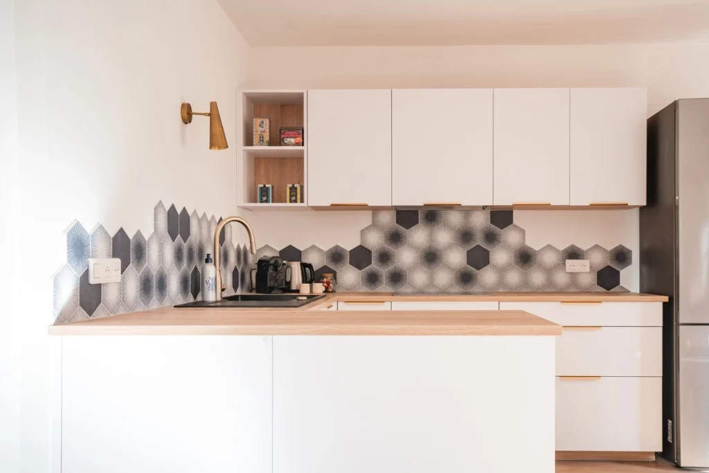 Cuisine blanche avec plan de travail en bois et crédence hexagonale, projet Val Saint-Jean par Maison Solthée, architecte d'intérieur à Aix-en-Provence