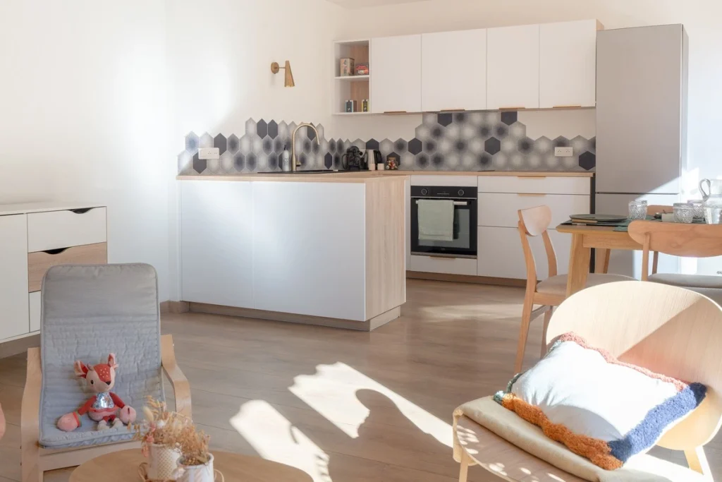 Cuisine blanche ouverte sur le séjour, crédence hexagonale noir et blanc, projet Val Saint-Jean par Maison Solthée, architecte d'intérieur à Aix-en-Provence