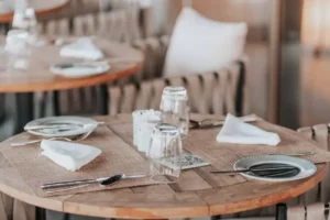 Table de restaurant dressée avec verres, serviettes et chaises tressées