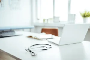 Bureau clair de cabinet médical avec stéthoscope, ordinateur portable et carnet