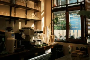Comptoir de café avec machine à espresso et étagères de verres, en lumière naturelle