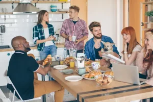 Colocataires réunis autour d'une grande table pour un petit-déjeuner dans une cuisine partagée