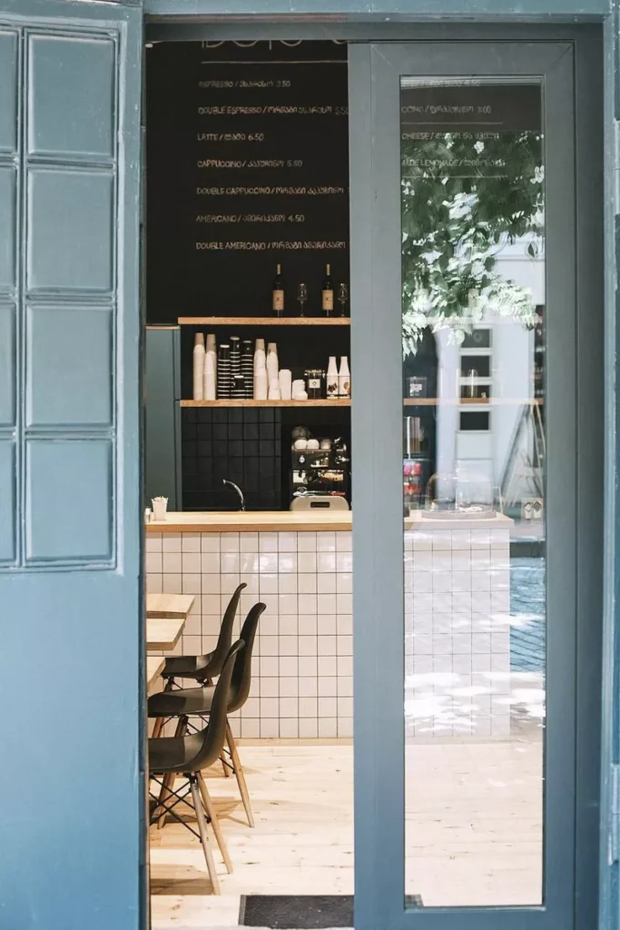 Projet Belvédère : porte vitrée bleu-gris ouvrant sur une salle de restaurant