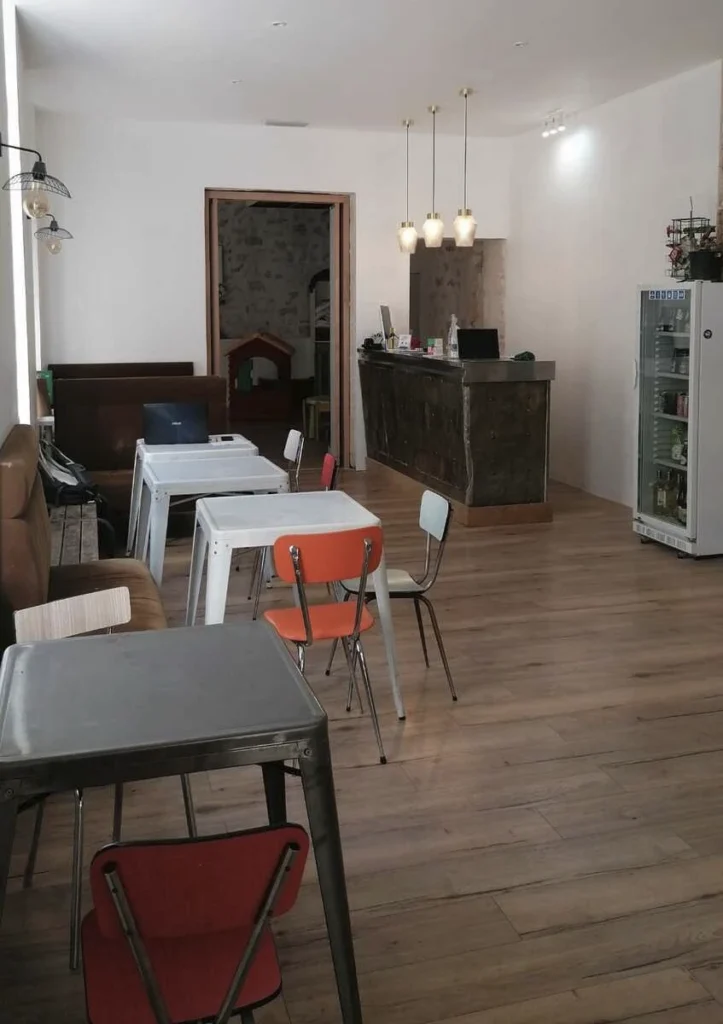 Salle du café associatif avec tables, chaises colorées et comptoir, projet Meinado par Maison Solthée, architecte d'intérieur à Marseille