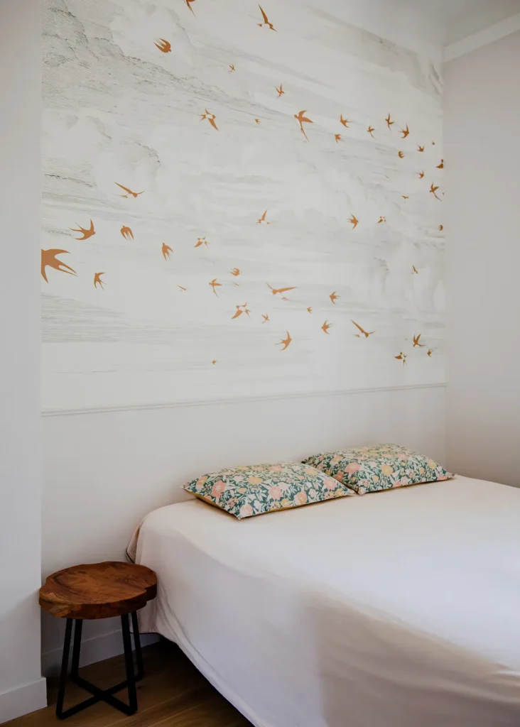 Chambre parentale avec mur blanc orné d'oiseaux dorés, lit et tabouret en bois, projet Barnabé par Maison Solthée, architecte d'intérieur à Marseille