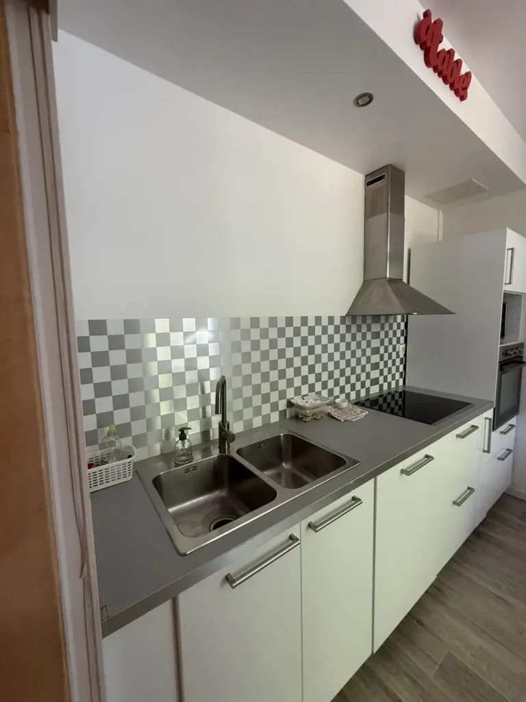 Cuisine avant travaux, meubles blancs, crédence à carreaux et sol gris, projet Barnabé par Maison Solthée, architecte d'intérieur à Marseille