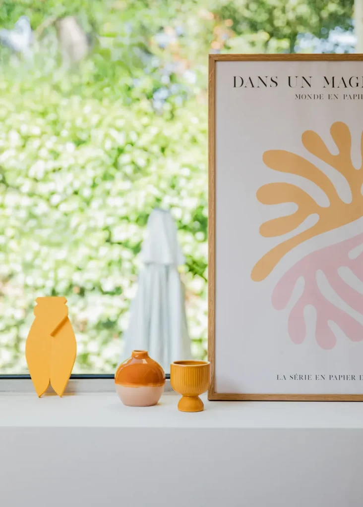 Affiche colorée, figurines en bois et vases sur un rebord de fenêtre, projet Barnabé par Maison Solthée, architecte d'intérieur à Marseille