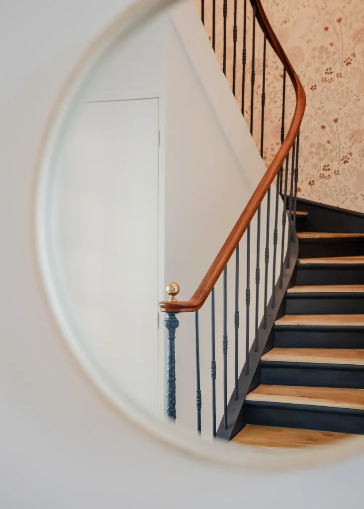 Escalier tournant reflété dans un miroir rond, rampe en bois et balustres noirs, projet Barnabé par Maison Solthée, architecte d'intérieur à Marseille