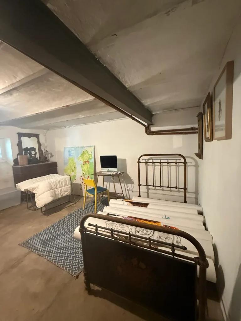 Avant travaux : pièce basse de plafond, lit en fer forgé, poutre et tuyaux apparents, projet Augustine par Maison Solthée, architecte d'intérieur à Cassis