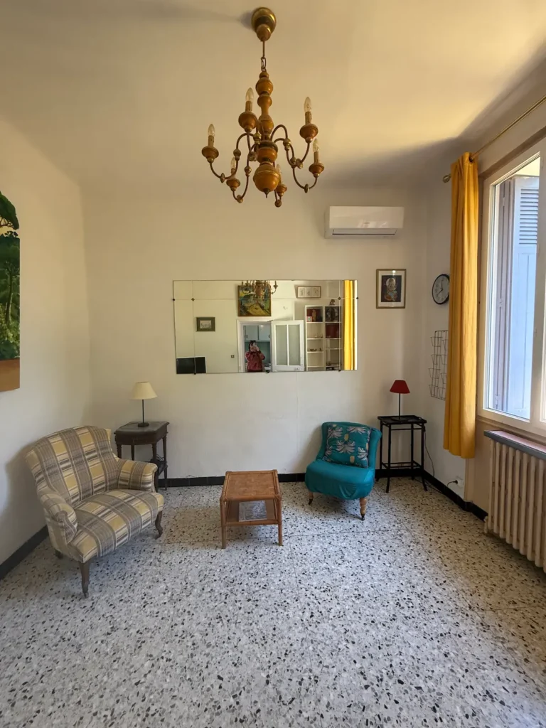 Avant travaux : pièce de vie avec lustre ancien, fauteuils et sol en carrelage moucheté, projet Augustine par Maison Solthée, architecte d'intérieur à Cassis