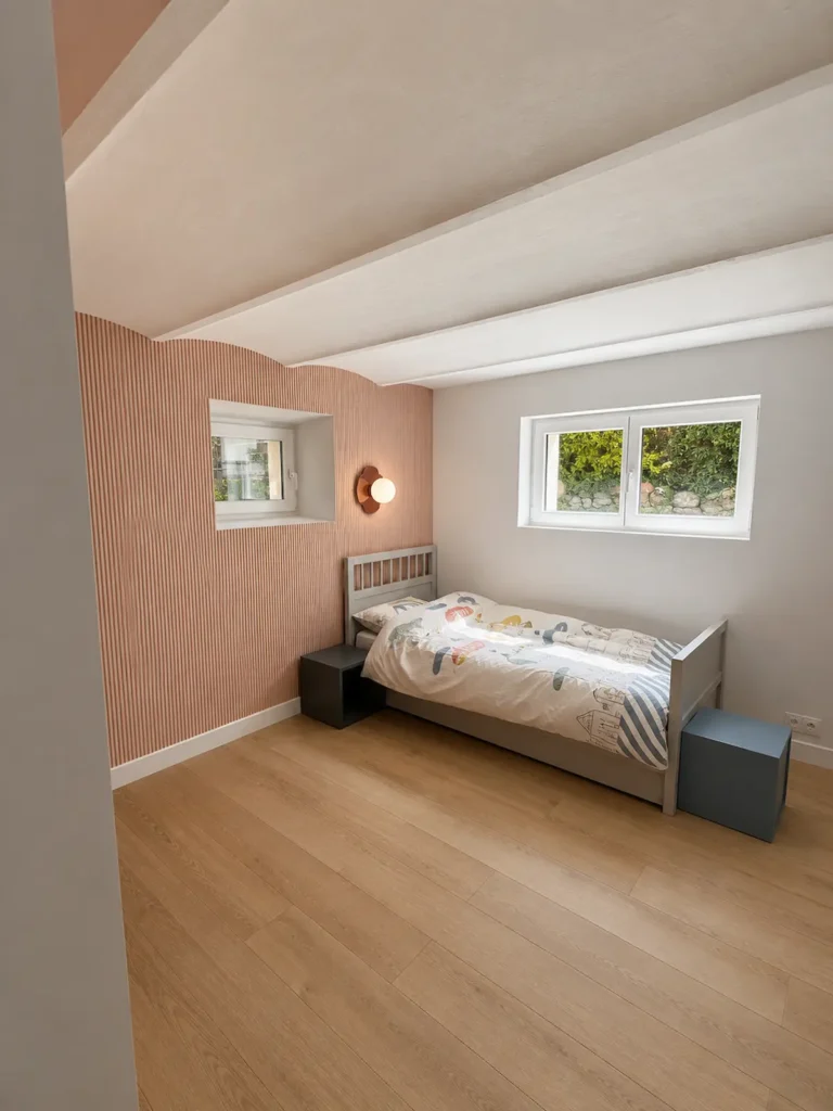 Chambre d'enfant au mur rose à lattes verticales, parquet clair et poutres blanches, projet Augustine par Maison Solthée, architecte d'intérieur à Cassis