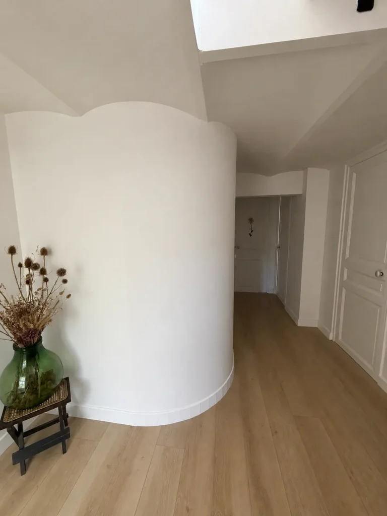 Palier avec cloison courbe blanche sous fenêtre de toit, parquet clair et vase en verre vert, projet Augustine par Maison Solthée, architecte d'intérieur à Cassis