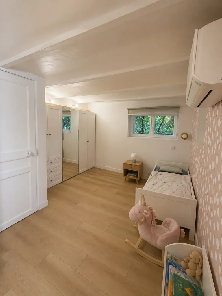 Chambre d'enfant au papier peint rose à motifs, rangements blancs et parquet clair, projet Augustine par Maison Solthée, architecte d'intérieur à Cassis